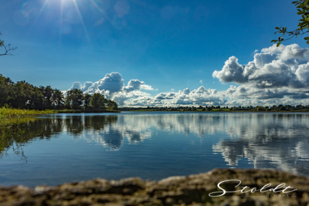 Nature and landscape photography showing a lake at midday with clouds reflecting in the water